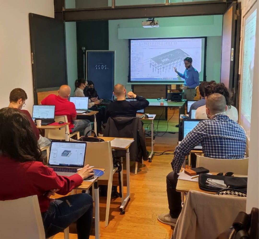Aula con partecipanti ai portatili e docente davanti a uno schermo proiettato