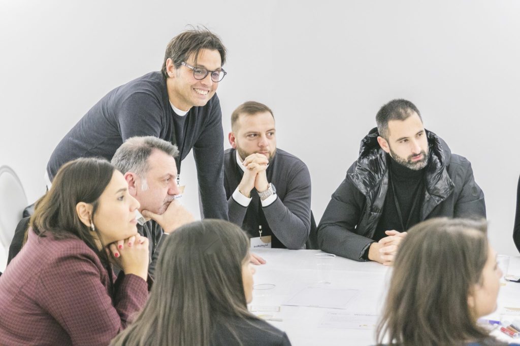Partecipanti attenti attorno a un tavolo durante una sessione di coaching di gruppo