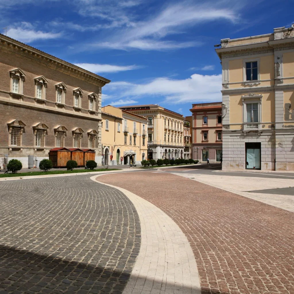 Piazza pavimentata con edifici storici sotto un cielo azzurro