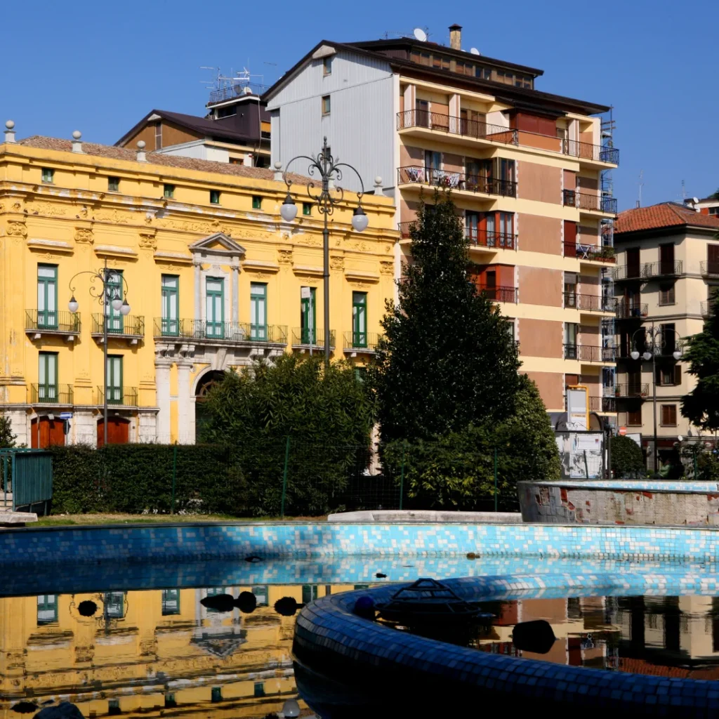 Palazzo giallo e fontana con acqua azzurra in una piazza cittadina