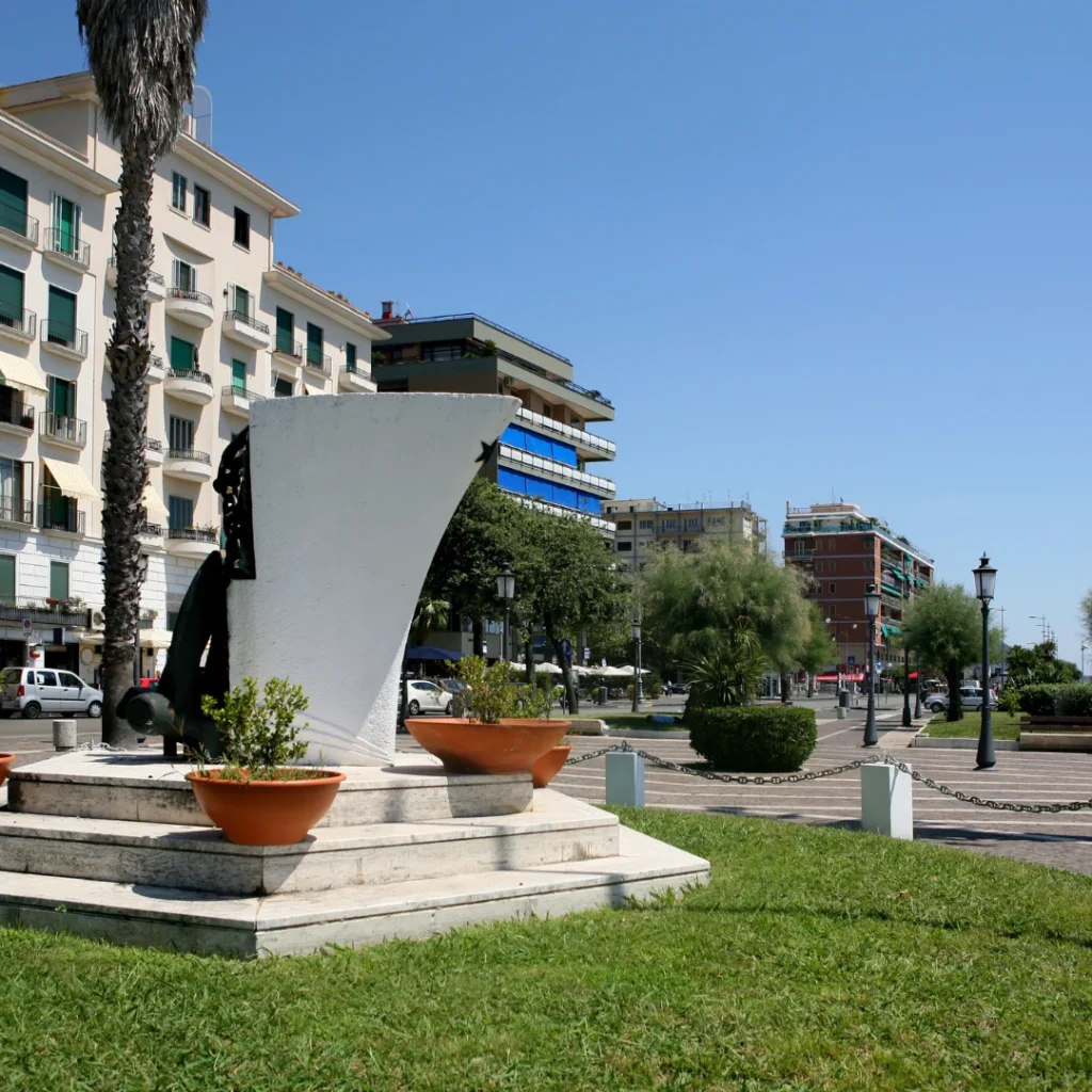 Monumento bianco su un prato davanti a edifici e palme
