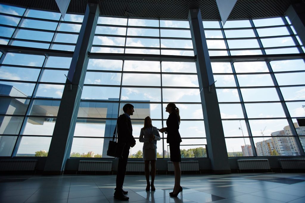 Silhouette di professionisti che parlano davanti a una grande vetrata