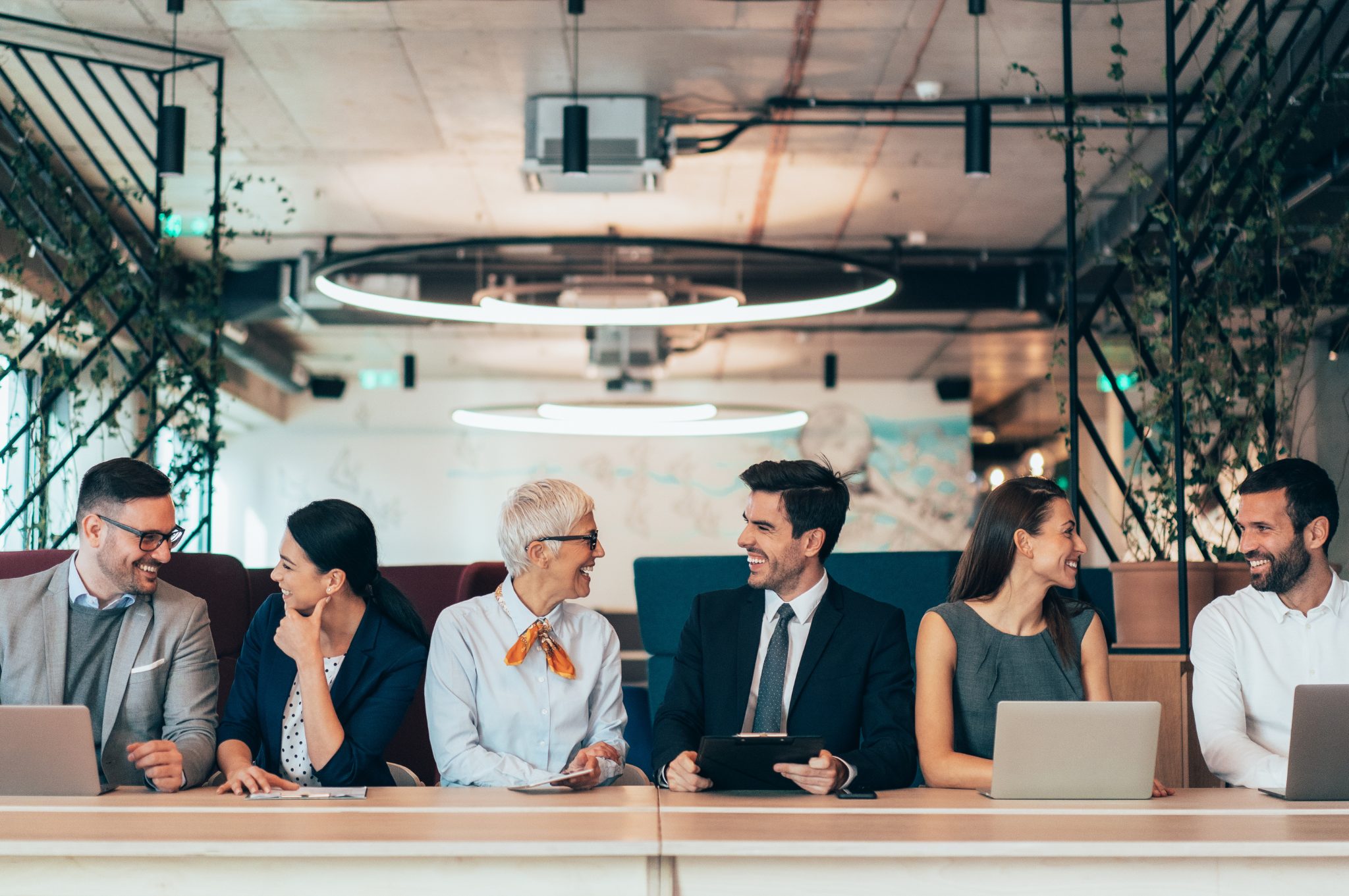 Gruppo di professionisti seduti in fila che conversano in un ufficio moderno