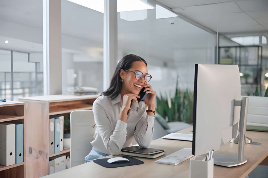 Donna sorridente al telefono alla scrivania di un ufficio