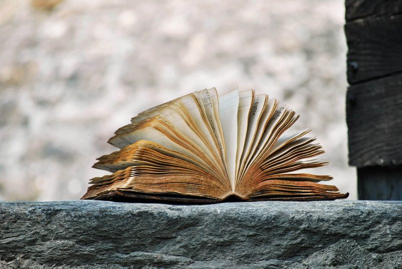 Libro antico aperto appoggiato su una pietra