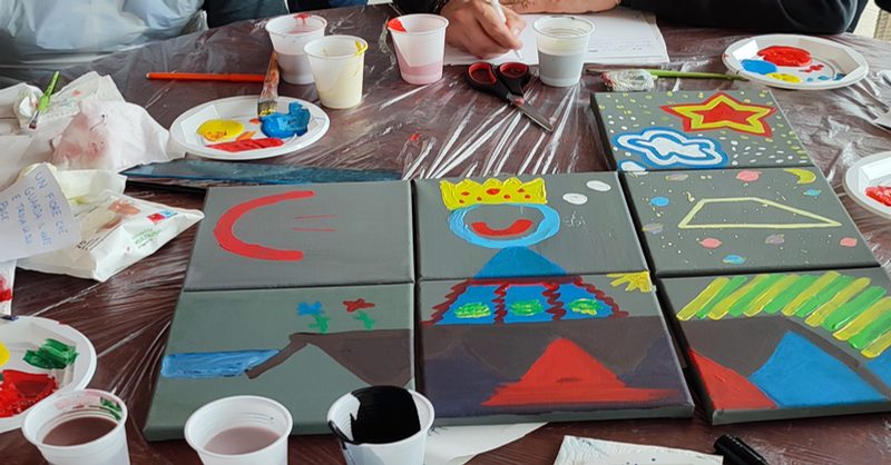 Tavolo con tele dipinte a mano e pennelli, attività creativa di gruppo