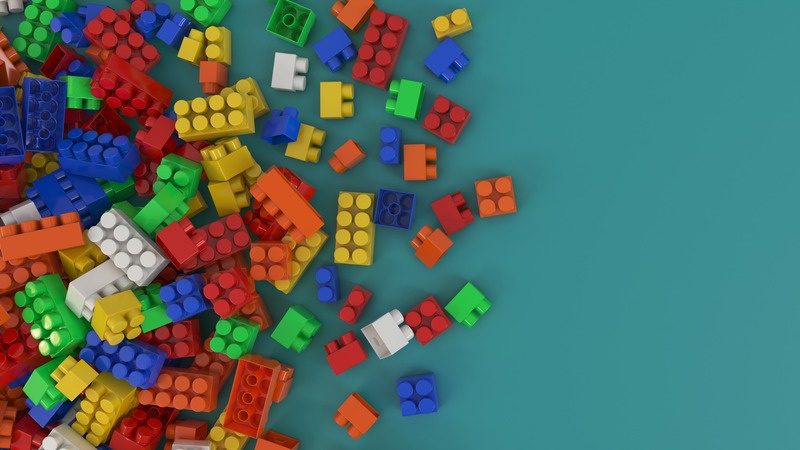 Mattoncini colorati sparsi su sfondo azzurro, gioco di costruzione