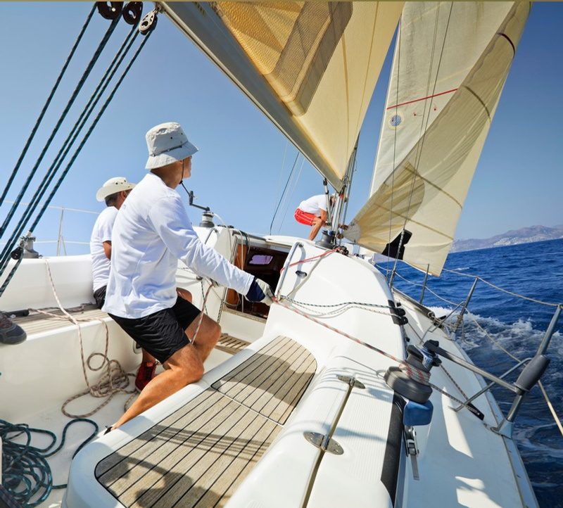Persona al timone di una barca a vela con le vele spiegate