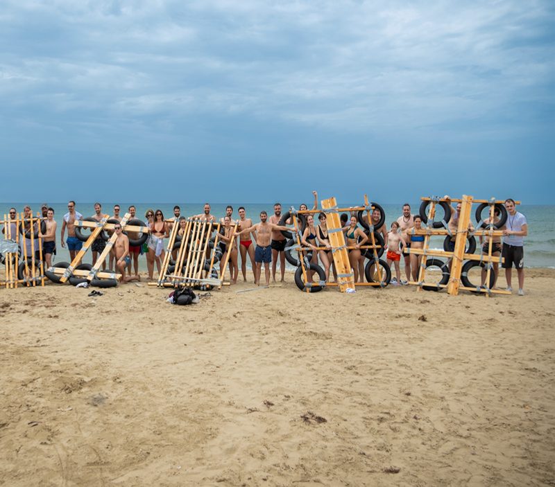 Gruppo di persone con zattere di legno costruite sulla spiaggia davanti al mare